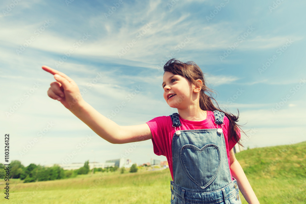 happy little girl pointing finger on summer field happy little girl pointing finger on summer field