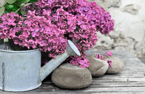 bouquet de lilas sur fond pierre avec petit arrosoir