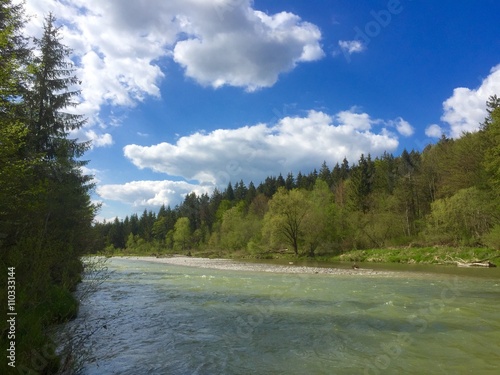 Isar fließt durch grüne Auen unter blauem Himmel photo