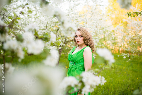 Beautiful happy young woman in spring blossoming garden