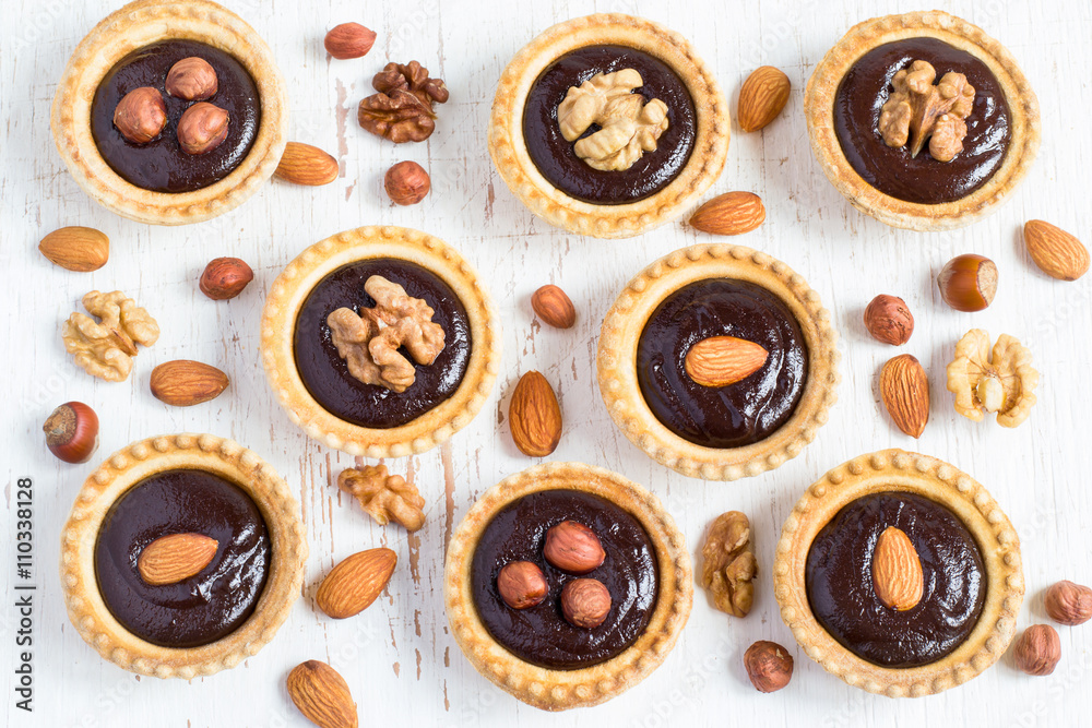 small Tarts with chocolate and different nuts on a white backgro small Tarts with chocolate and different nuts on a white backgro