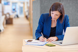 Businesswoman working on paperwork at her desk in shared office