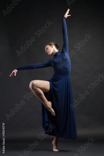 Posing dancer in blue dress over dark background