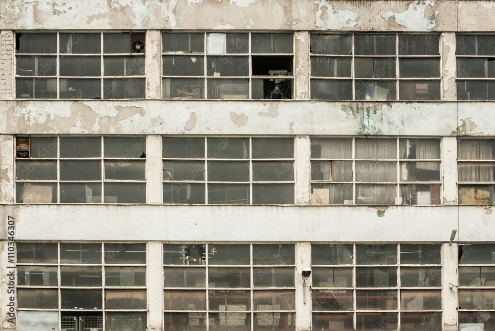 Facade of obsolete weathered grunge industrial building as background