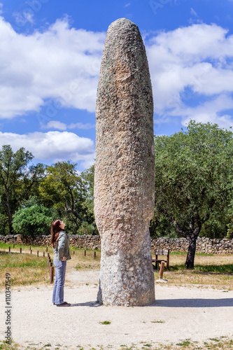 Woman looking at the Standing Stone / Menhir of Meada, the largest of the Iberian Peninsula. A mysterious phallic monument from prehistory, representing fertility. Castelo de Vide, Portugal. photo