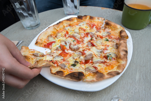 A small pizza on plate with piece being taken