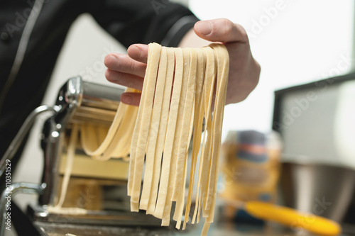 human hand with pasta from machine;