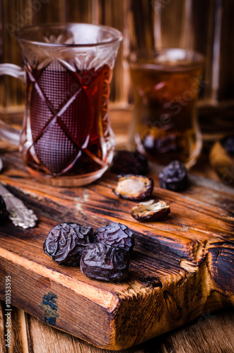 Dates with tea cup on vintage wooden background. Selective focus. Toned image