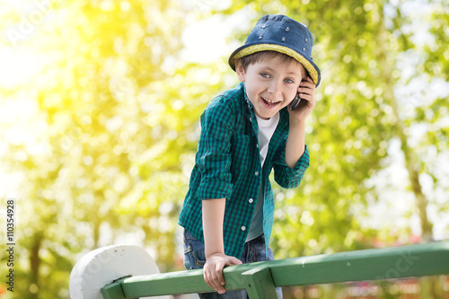 the boy delightfully and emotionally speaks by phone on a bench in spring park