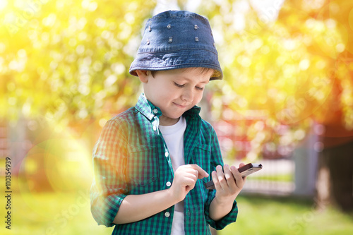 the boy in a hat in park in the spring with phone
