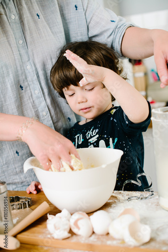 Little boy helping his mother with the baking in the kitchen sta photo