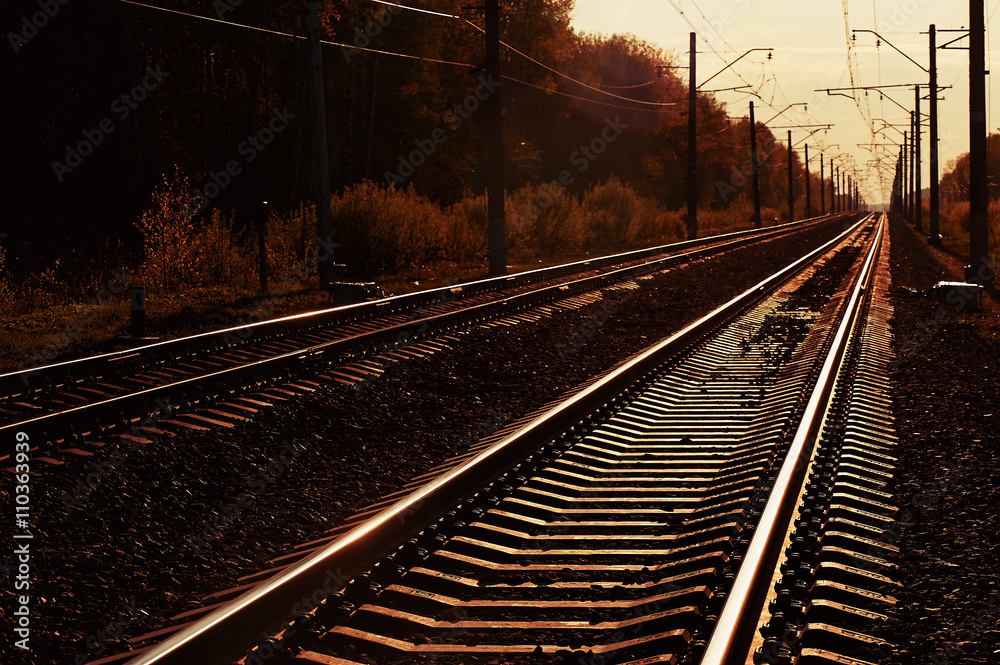Obraz premium junction of railways track in trains station against beautiful light of sun set sky use for land transport and logistic industry background ,backdrop,copy space theme