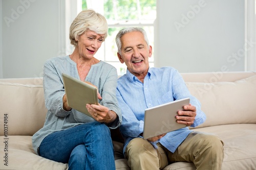 Smiling senior couple using digital tablet at home