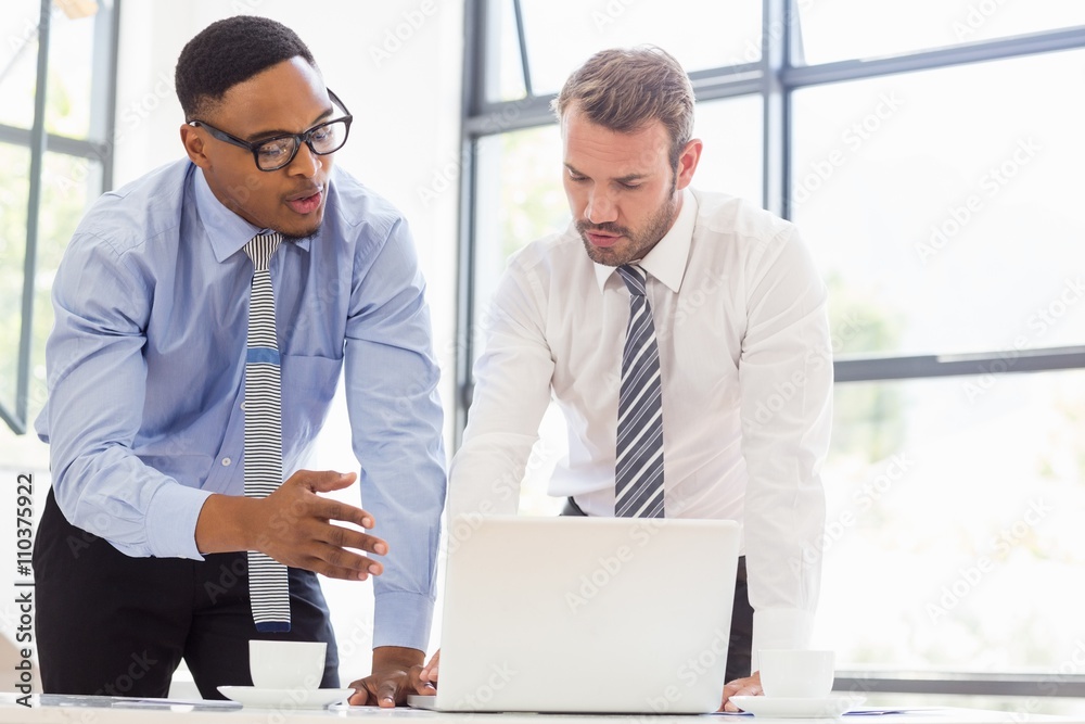 Businessmen using laptop at desk Businessmen using laptop at desk