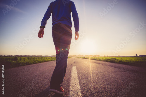 Man walking on the line on a paved road