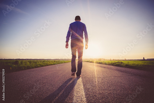 Man walking on the line on a paved road photo