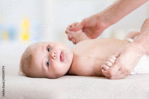 Baby 5 months massaging. Kid lying on the back