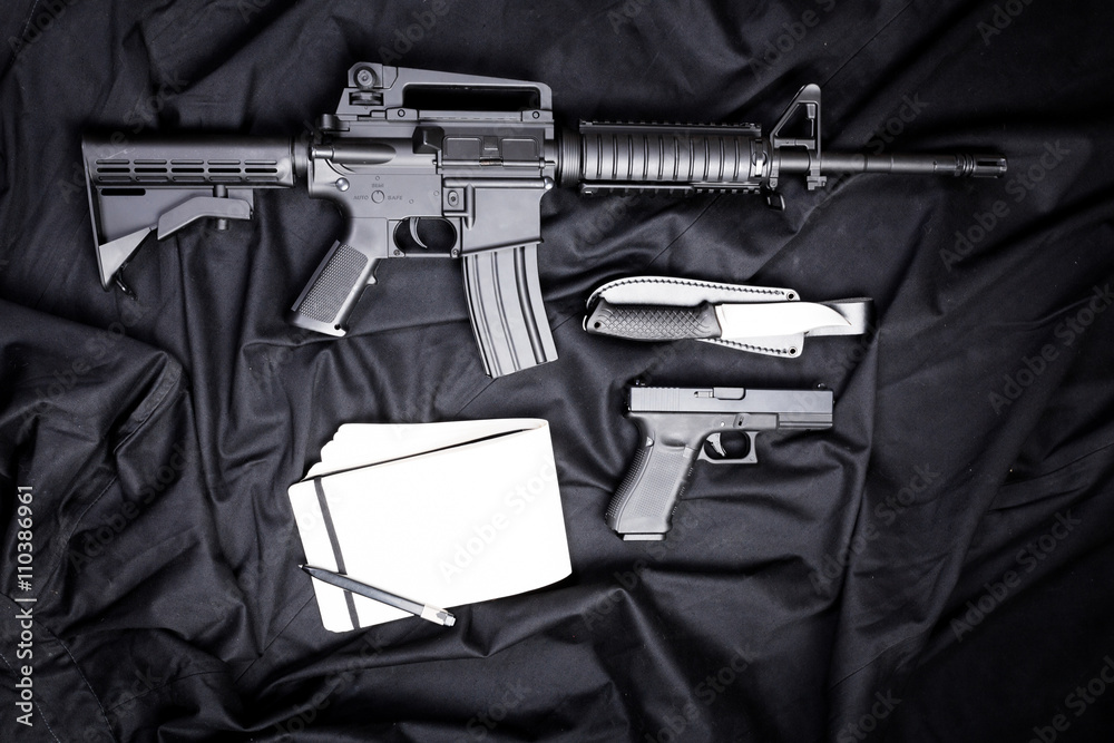 Rifle, gun, knife with sheath, compass and notebook with pen on on black cloth Rifle, gun, knife with sheath, compass and notebook with pen on on black cloth