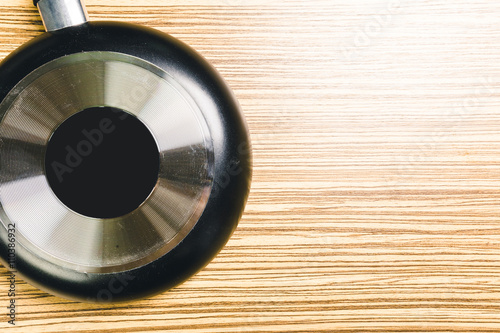 Frying pan on wooden table background. View from above