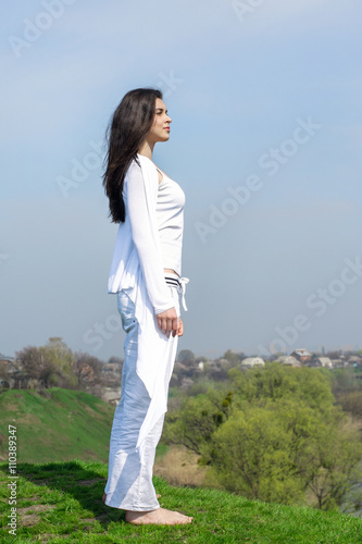 Girl doing yoga exercise standing on a hill