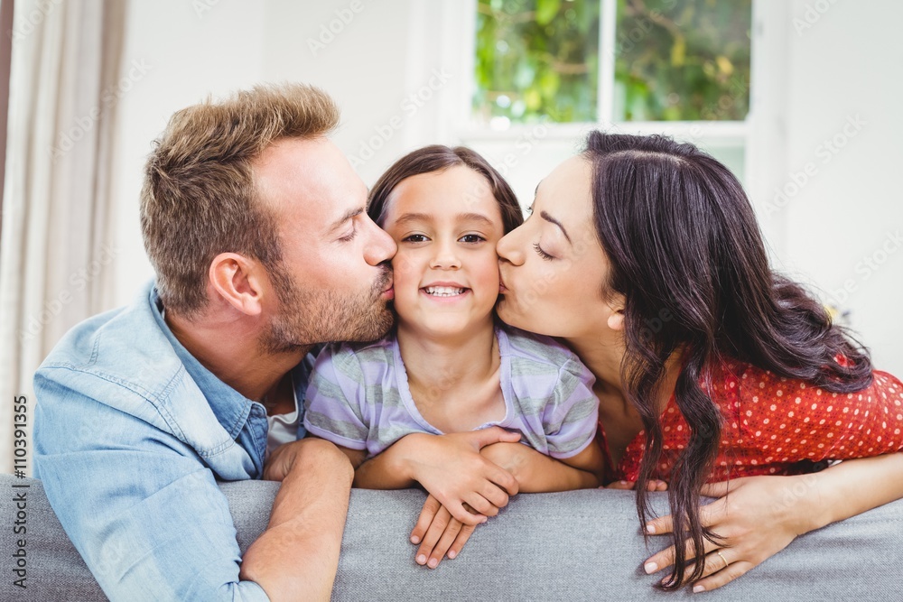 Mother and father kissing daughter at home Mother and father kissing daughter at home