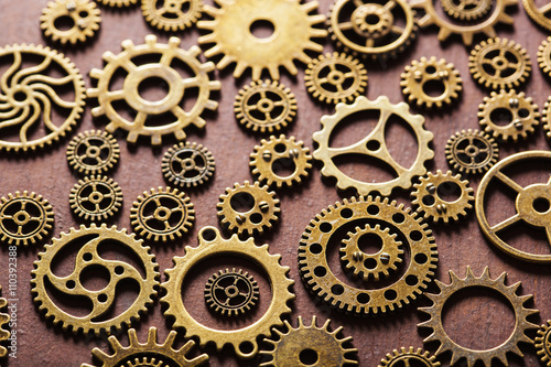steampunk mechanical cogs gears wheels on wooden background © Olga Miltsova