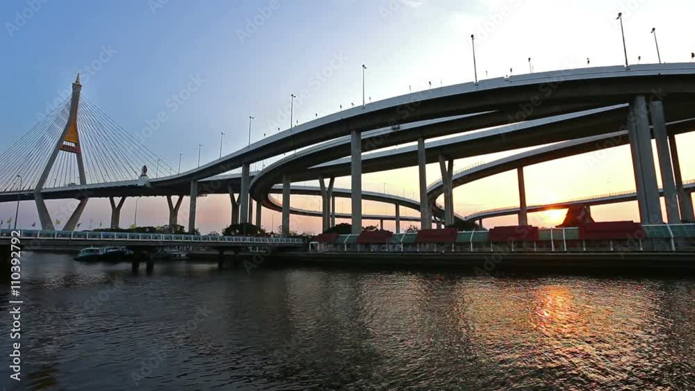 Modern Suspension bridge and highway curved riverside at sunset scene with golden light and water wave and shadow reflection Modern Suspension bridge and highway curved riverside at sunset scene with golden light and water wave and shadow reflection