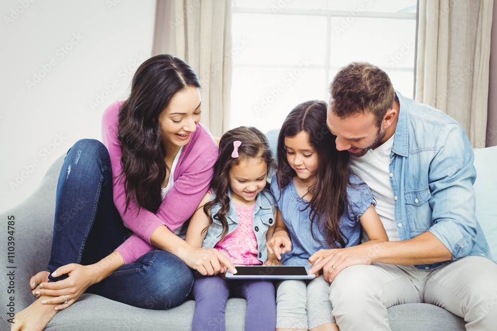 Family looking in tablet computer while sitting on sofa
