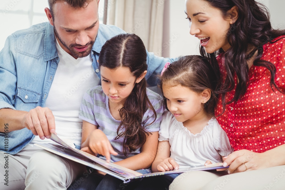 Family looking in picture book while sitting on sofa Family looking in picture book while sitting on sofa