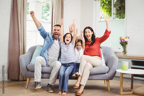 Obraz na płótnie Happy family cheering while siting on sofa