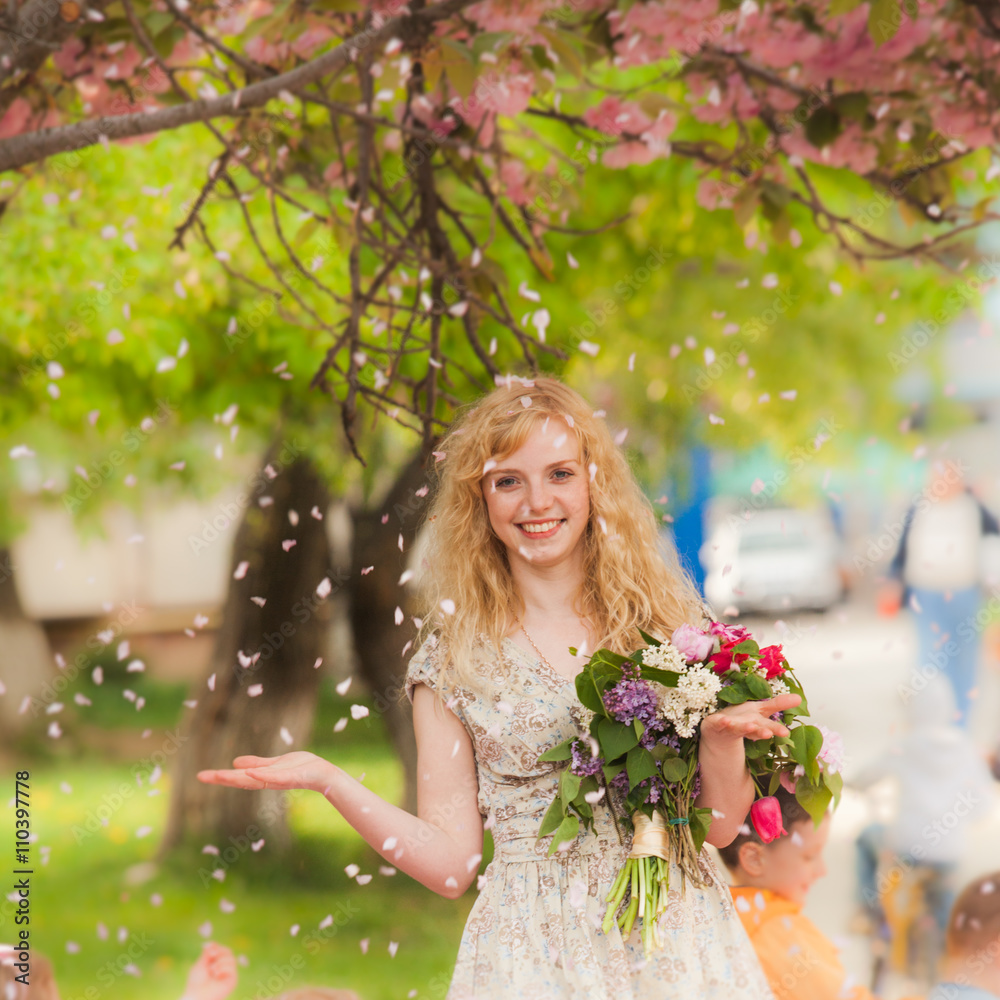 Fototapeta premium Smiling girl under sakura blossoms