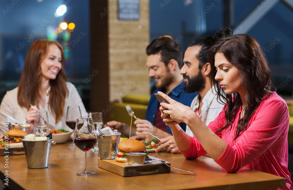 woman with smartphone and friends at restaurant woman with smartphone and friends at restaurant