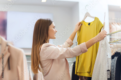 happy young woman choosing clothes in mall