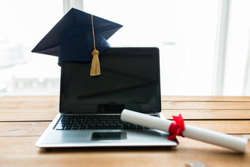 close up of laptop with mortarboard and diploma