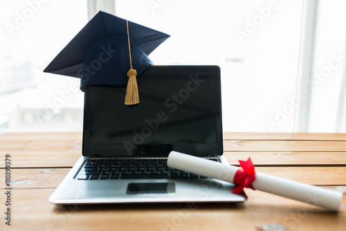 close up of laptop with mortarboard and diploma