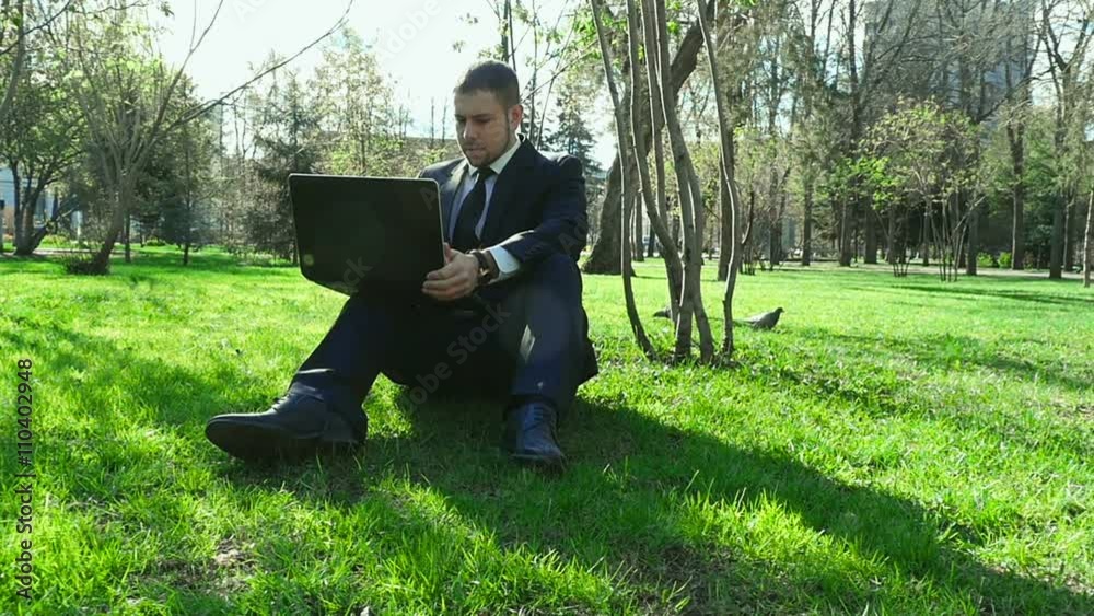 Businessman works with laptop in the city park Businessman works with laptop in the city park