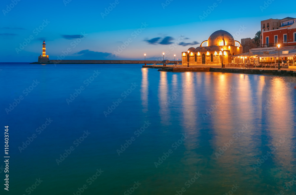 Picturesque view of Venetian quay of Chania with Lighthouse and Kucuk Hasan Pasha Mosque during mornng blue hour before sunrise, Crete, Greece