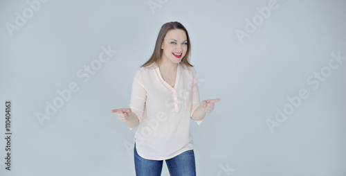 Young positive woman with a wide smile pointing fingers left and right, gray background, copy space, panorama. © 060808