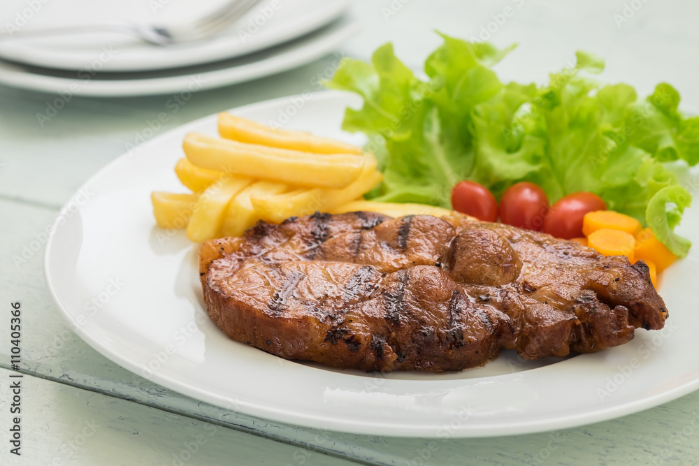 Grilled steak with french fries and vegetables on plate