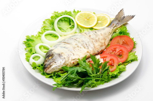 Grilled fish with white sauce on fresh vegetables