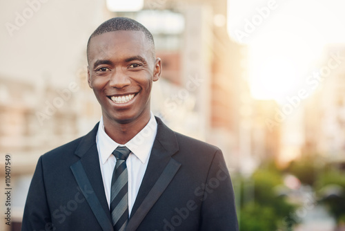 African businessman standing outside in a city smiling broadly
