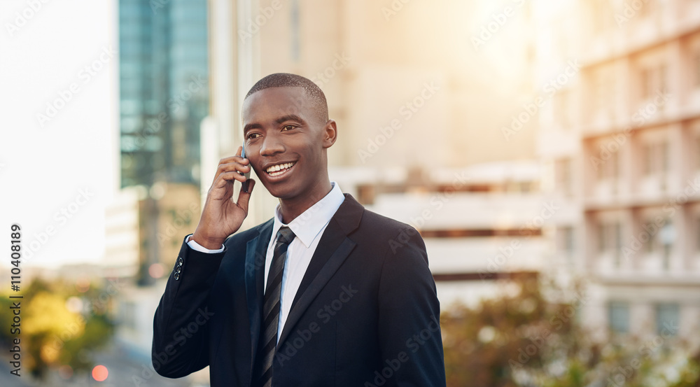Smart young African businessman talking on his phone in city Smart young African businessman talking on his phone in city