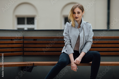 Young woman sitting on the bench in front of buindings photo