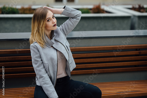 Young woman sitting on the bench in front of buindings © Serhiy Hipskyy