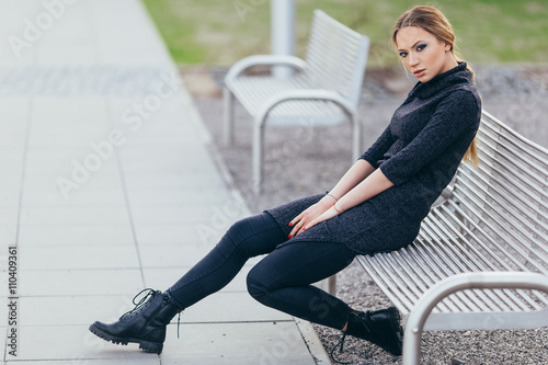 Young woman sitting on the bench in front of buindings photo