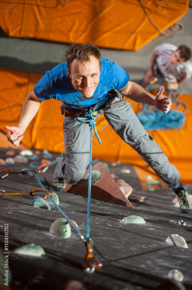 Man with climbing equipment hanging on a rope an indoor rock
