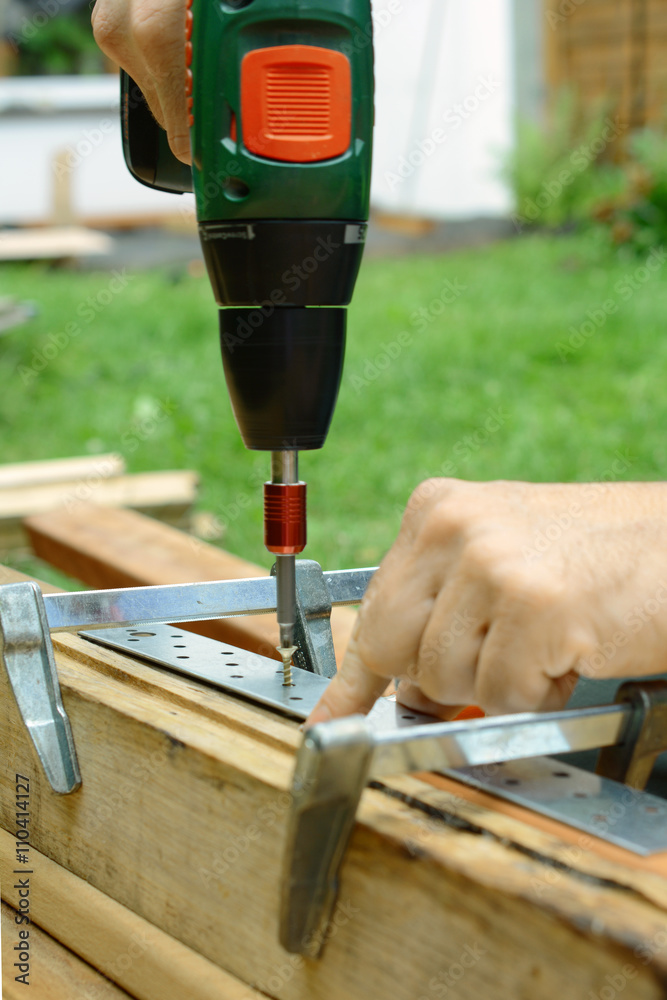 Schreiner schraubt Schraube mit Akkuschrauber in Holzbalken für Terrasse  Stock-Foto | Adobe Stock