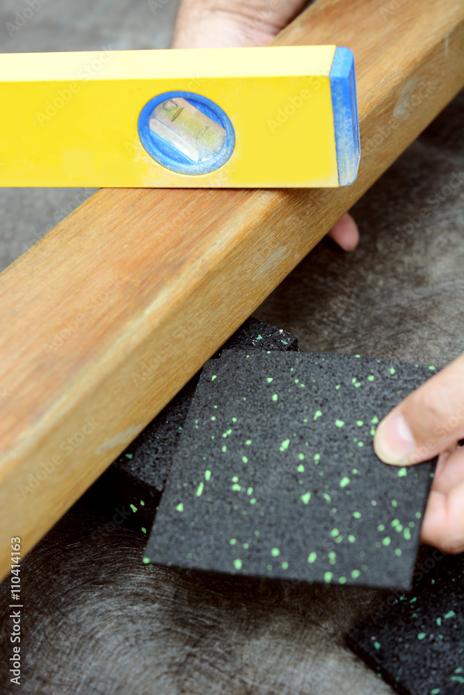 Schreiner oder Handwerker setzt Granulatpad aus Bautenschutzmatte unter  Holzbalken für Terrasse Stock-Foto