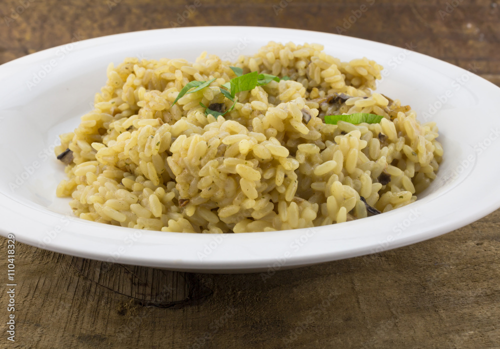 Mushroom risotto close up in white plate on wood Mushroom risotto close up in white plate on wood