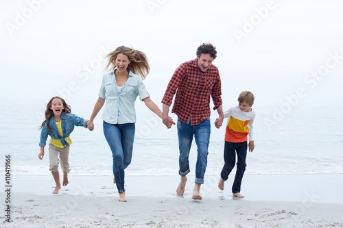 Happy family holding hands while running at sea shore